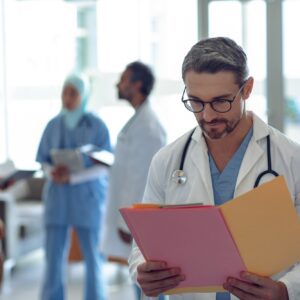 Caucasian male doctor looking at medical file in hospital.